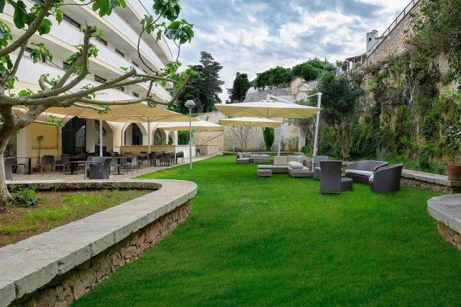 Giardino con sedute, tavoli e tende da sole.