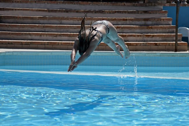 Donna in bikini che tuffa in piscina.