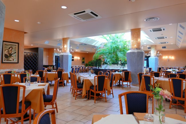 Ristorante elegante con tavoli apparecchiati e piante decorative.