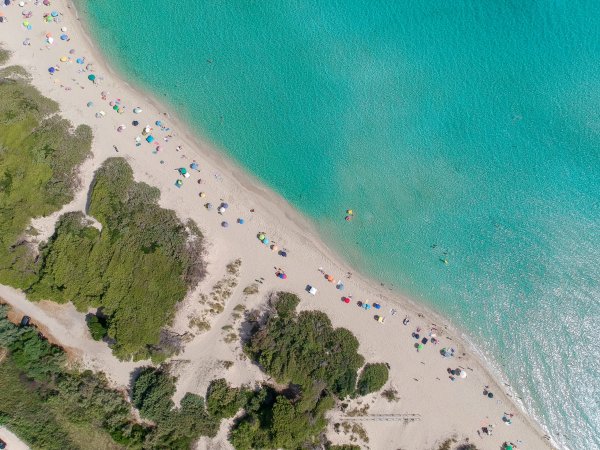 Spiaggia con ombrelloni colorati e mare turchese.