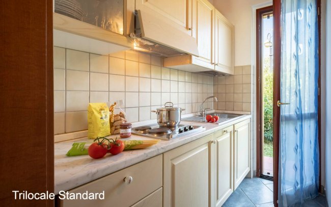 Cucina con piano in marmo, pomodori, e luce naturale.