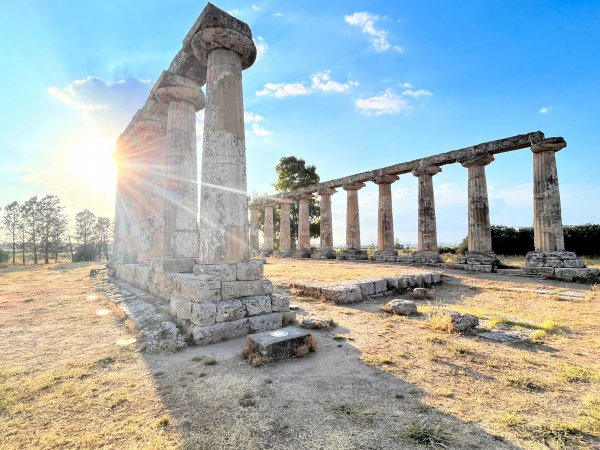Rovine di un tempio antico con colonne illuminate dal sole.