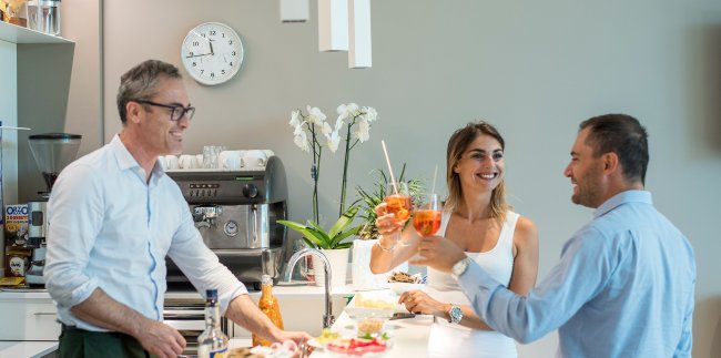 Persone che brindano in una cucina moderna.