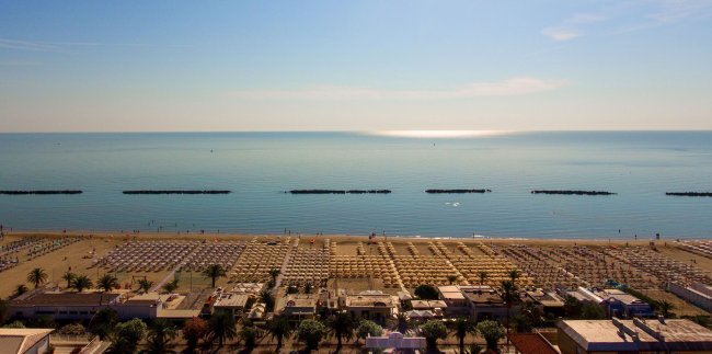 Spiaggia vista dall'alto con mare calmo.