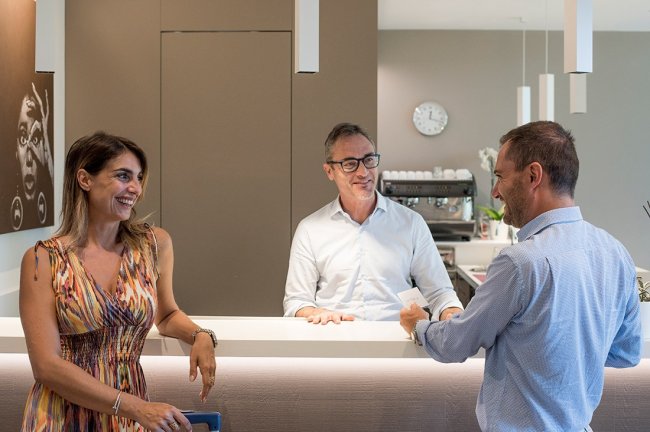 Tre persone interagiscono alla reception di un hotel.