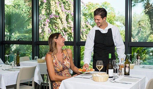 Cliente che riceve un piatto al ristorante da un cameriere sorridente.