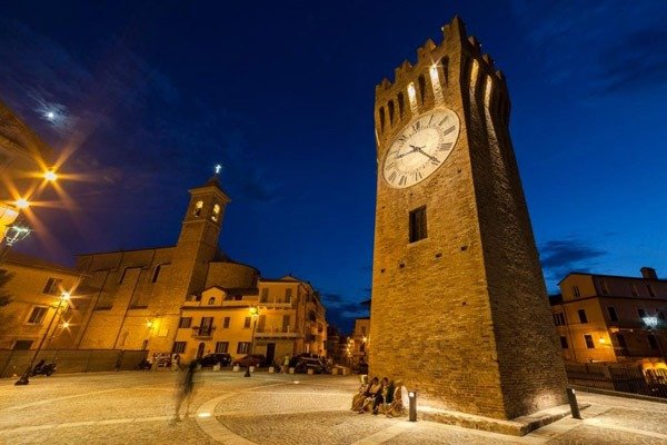 Torre dell'orologio in una piazza di sera.