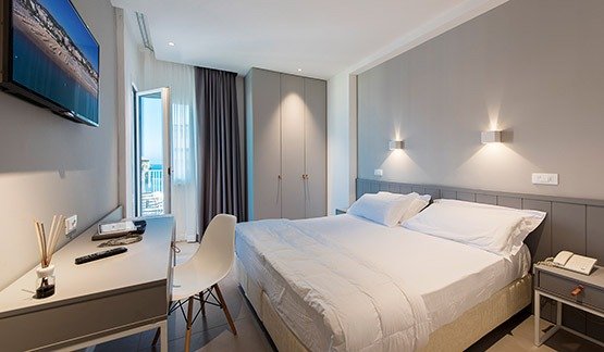 Stanza moderna con letto matrimoniale e TV a parete.