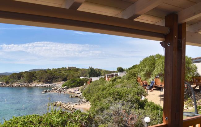 Vista su un mare calmo da una terrazza con vegetazione.