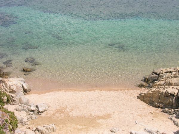 Spiaggia tranquilla con acqua cristallina e rocce.