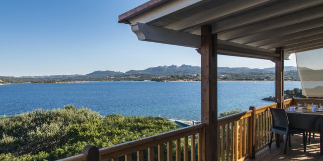 Vista sul mare da una terrazza con ringhiera in legno.