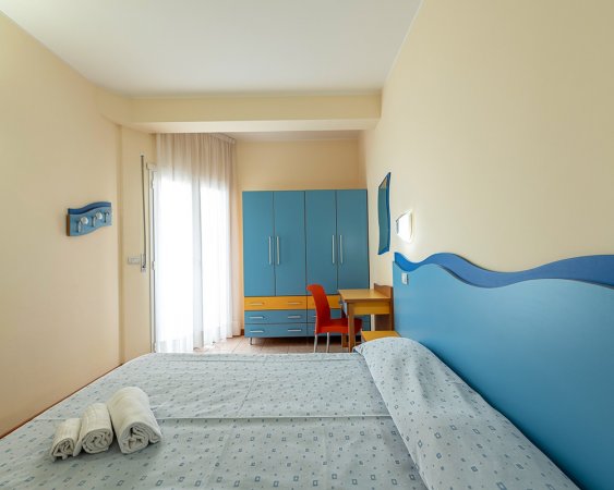 Camera da letto con letto matrimoniale e arredamento blu.