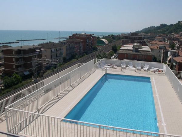 Piscina sul tetto con vista sul mare e palazzi circostanti.