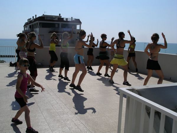 Persone che fanno fitness su una terrazza con vista mare.