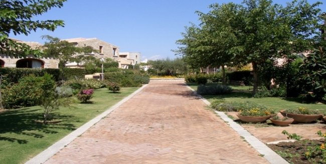 Viale con giardini e edifici in pietra.