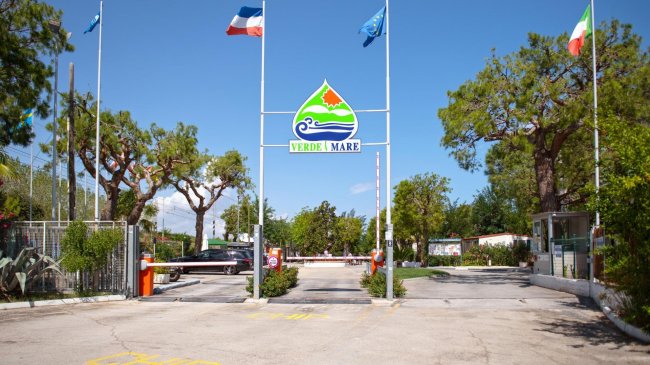 Ingresso di un campeggio con bandiere e cartello 