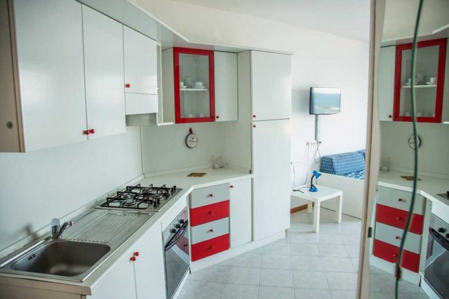 Cucina bianca e rossa con piano cottura.
