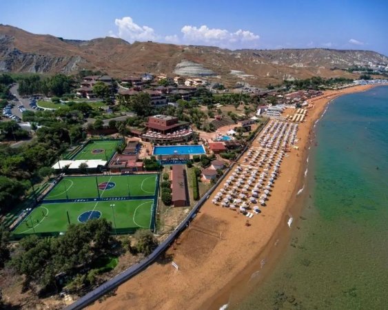 Resort con campi sportivi, piscina e spiaggia con ombrelloni.