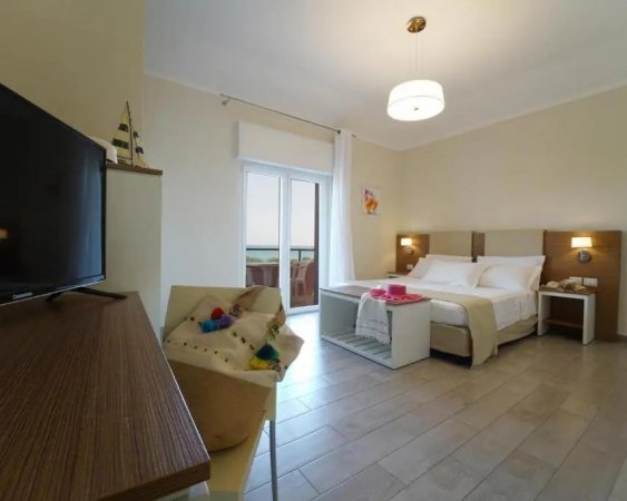 Camera d'hotel con letto matrimoniale, TV, balcone e decorazioni nautiche.