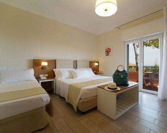 Camera d'hotel con letti e balcone vista mare.