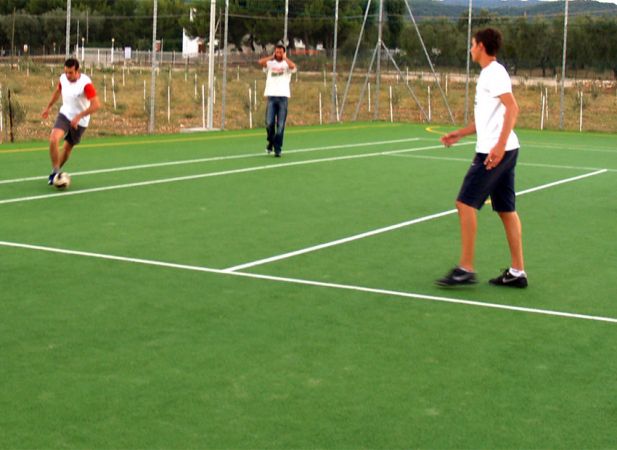 Tre persone giocano a calcio su un campo verde.