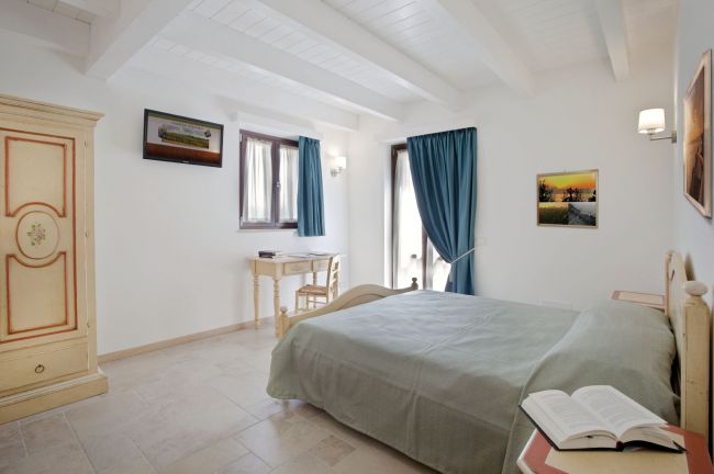 Camera da letto con letto matrimoniale, armadio dipinto, scrivania e tende blu.