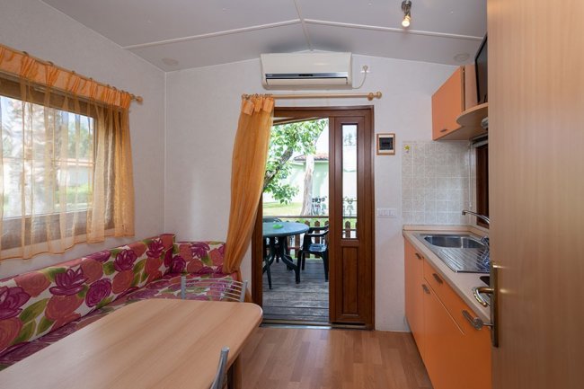 Cucina con tavolo, divano e porta aperta sul giardino.