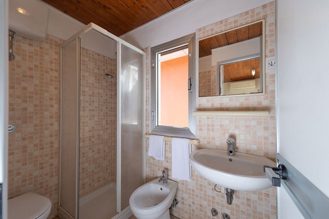Bagno con doccia, lavabo e bidet, piastrelle beige.