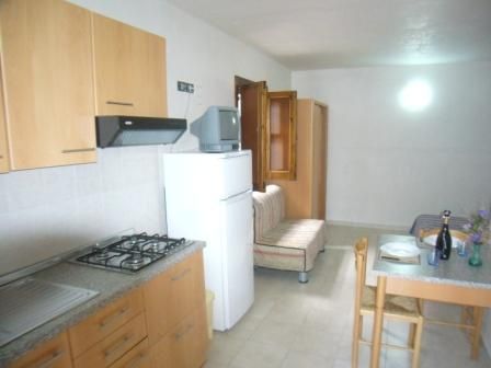 Cucina con mobili in legno, frigorifero bianco e tavolo da pranzo.