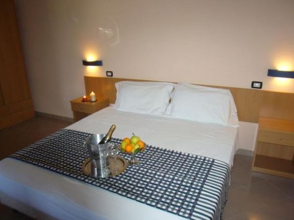 Camera con letto matrimoniale, candele e frutta fresca.