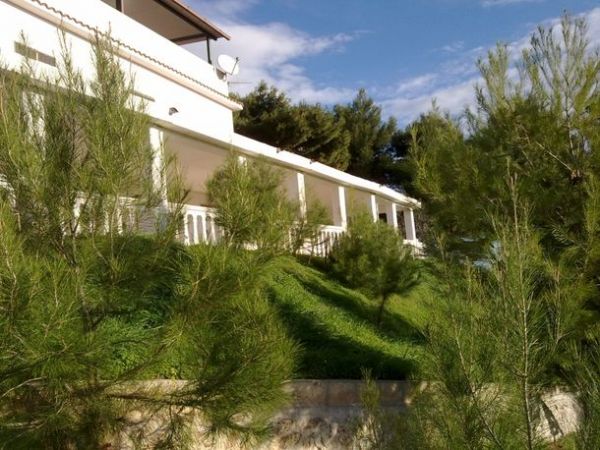 Una villa immersa nel verde con balconi e un tetto spiovente, vista dal giardino.