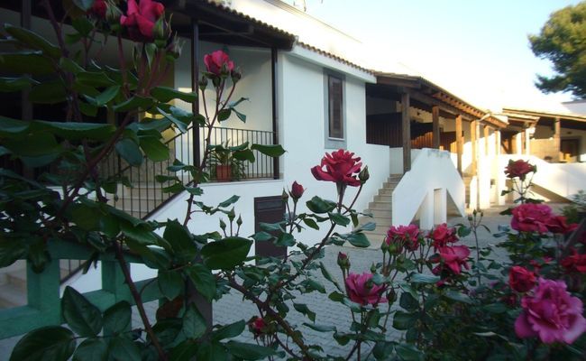 Una casa bianca con rose rosse in primo piano.