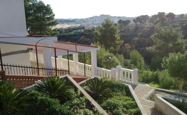 Vista di una terrazza con ringhiera bianca e un panorama collinare sullo sfondo.