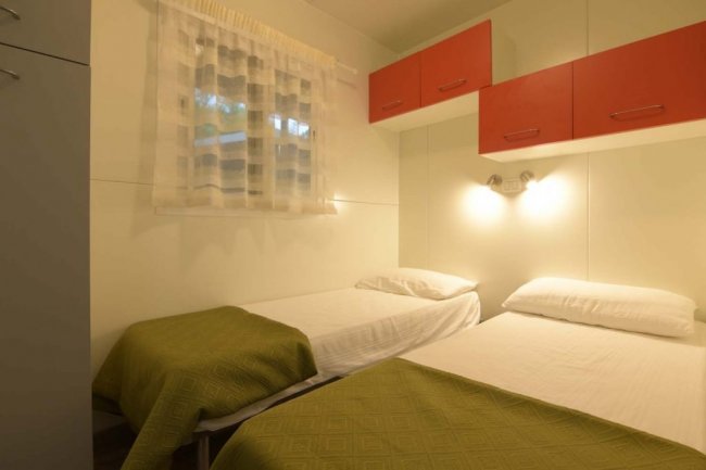 Camera con due letti singoli e armadi sopraelevati.