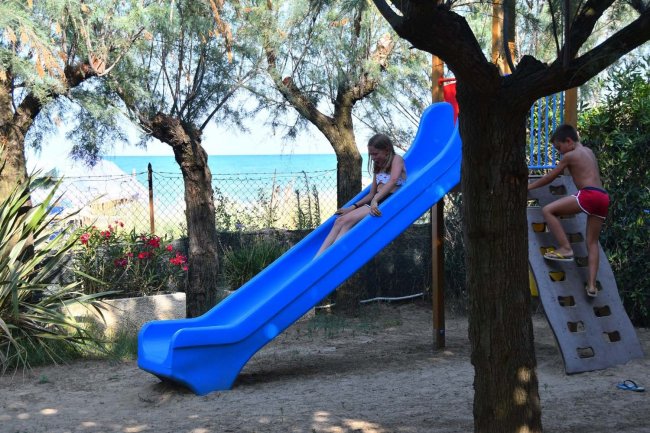 Bambini giocano su uno scivolo blu e una parete da arrampicata.