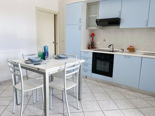 Cucina moderna con mobili azzurri e tavolo bianco apparecchiato.