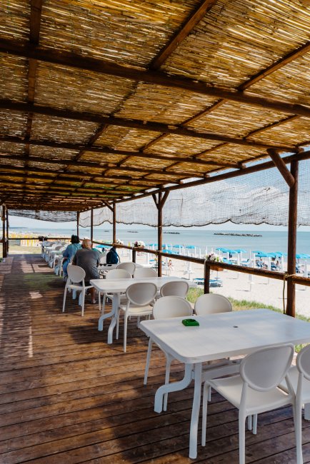 Terrazza con tavoli bianchi e vista mare.