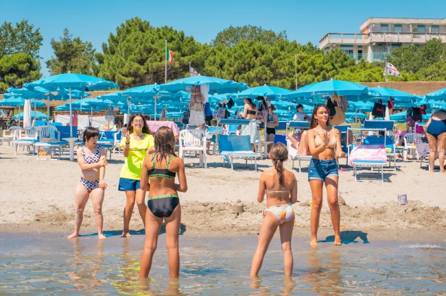 Persone in spiaggia con ombrelloni blu.