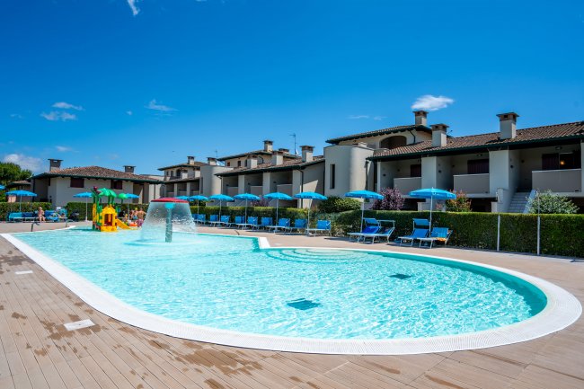 Piscina all'aperto con lettini e ombrelloni.