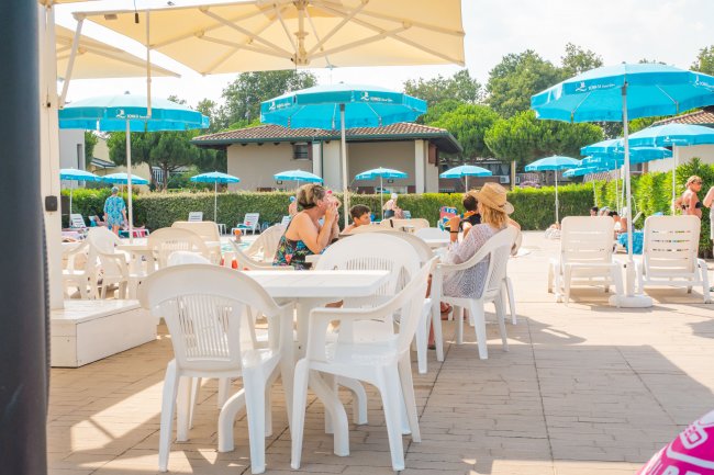 Persone sedute a tavoli all'aperto con ombrelloni blu.