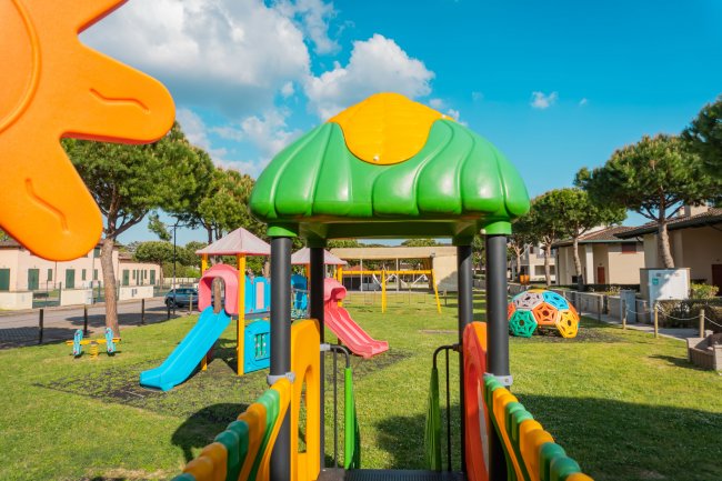 Parco giochi colorato con scivoli e strutture verdi.