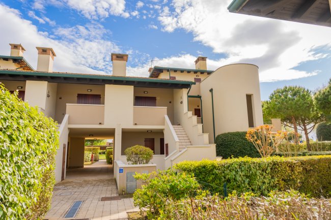 Complesso residenziale beige con scale e vegetazione.