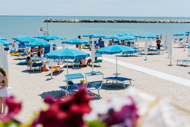 Spiaggia con ombrelloni blu e lettini.