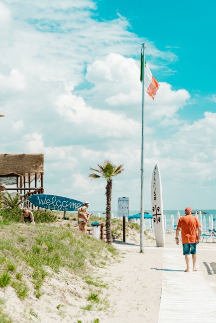 Uomo su passerella di sabbia verso il mare.