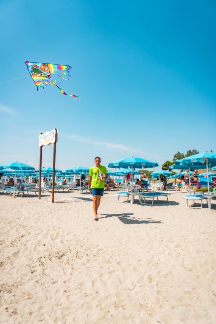 Uomo su spiaggia con aquilone colorato.