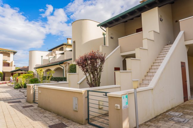 Complesso residenziale moderno con scale e giardino.