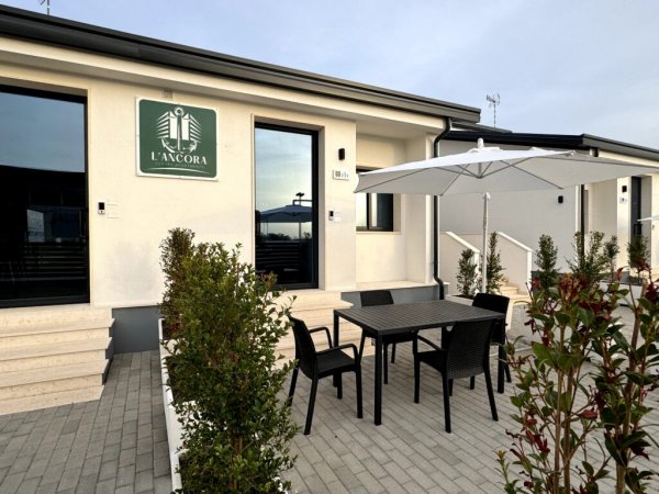 Spazio esterno con tavolo, sedie e ombrellone davanti a un edificio.