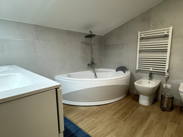 Bagno moderno con vasca angolare, doccia e bidet.