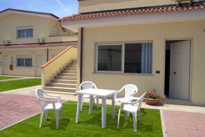 Esterno di una casa con mobili da giardino bianchi su prato.