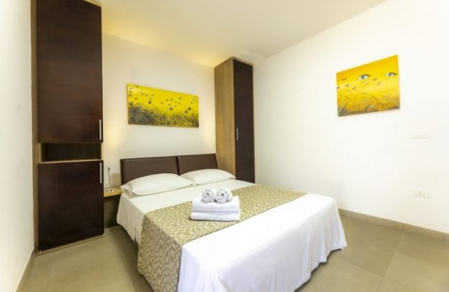 Camera con letto matrimoniale, armadi e quadro giallo.